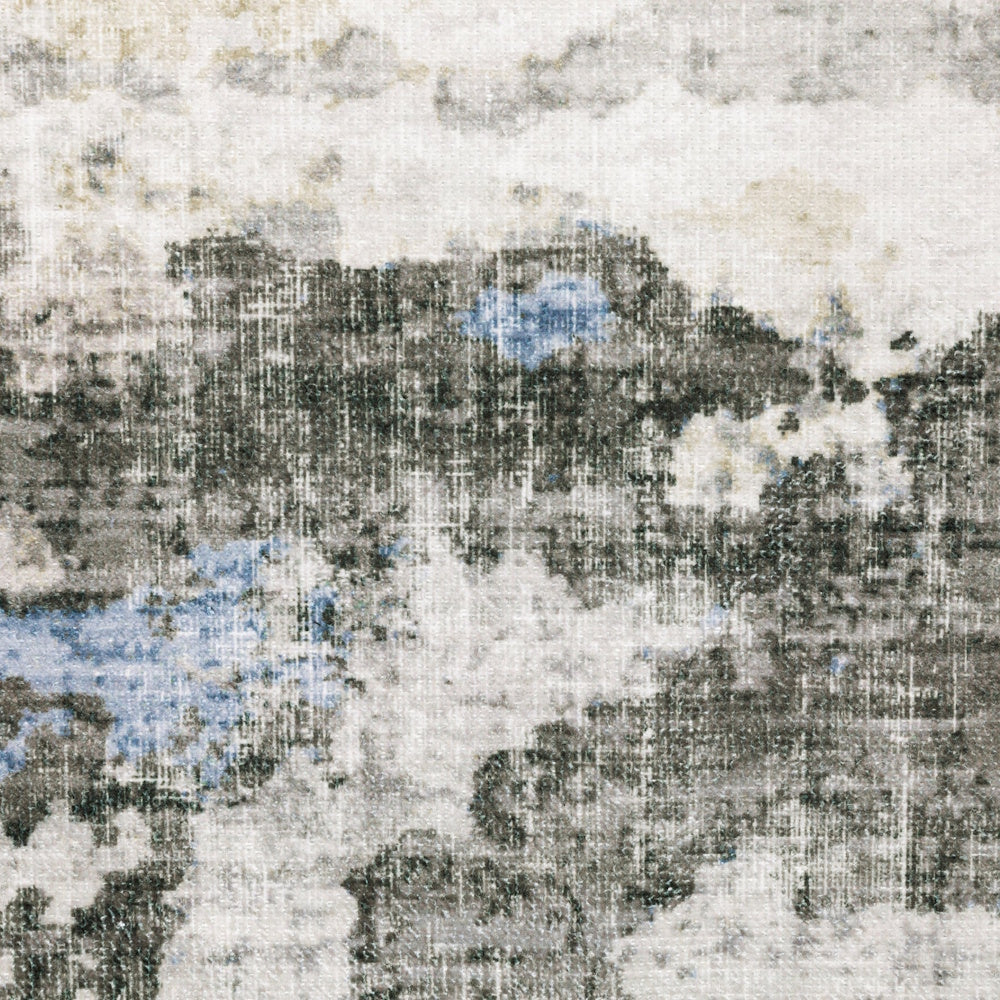 Close-up of an abstract rug pattern with distressed textures in cream, gray, and pops of blue.