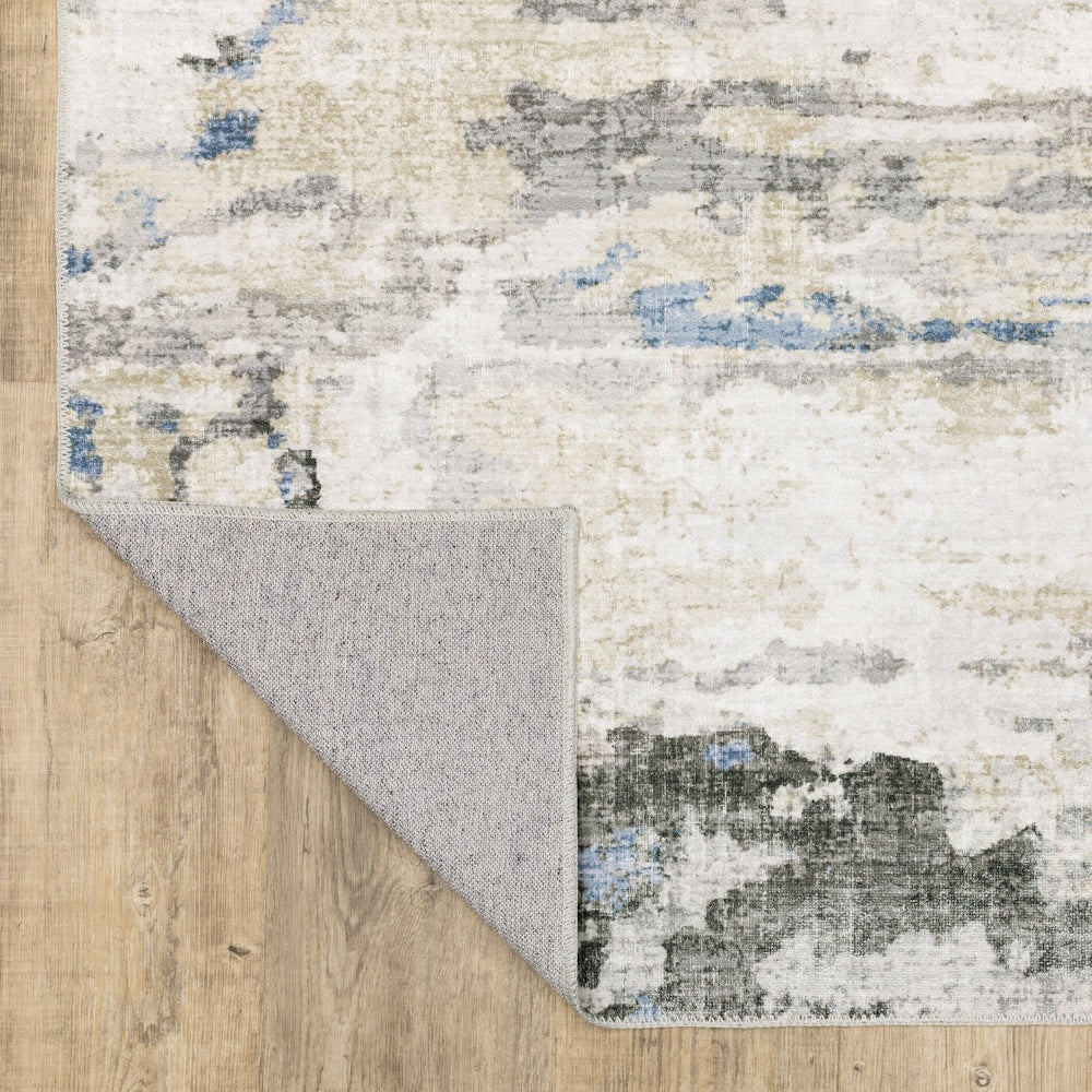 Abstract area rug with blue and grey patterns, showing a folded corner to reveal the non-slip backing.