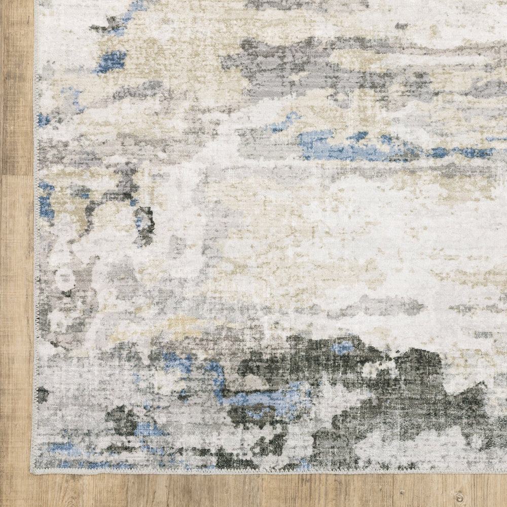 Abstract area rug with a distressed pattern in cream, gray, beige, and blue on a wood floor.