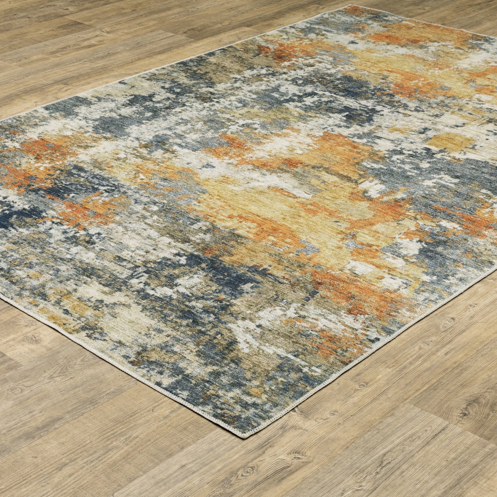 An abstract area rug with orange, blue, and cream distressed patterns on a wood floor.