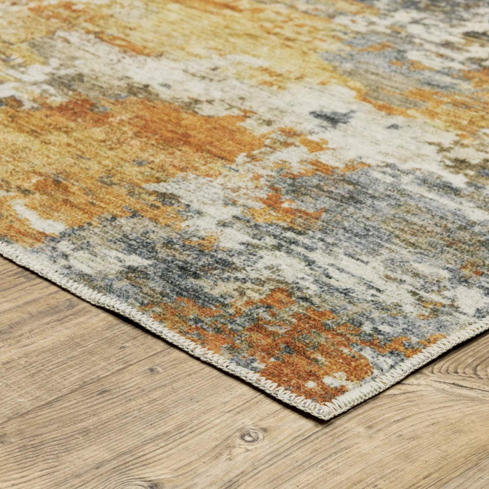 Close-up of the corner of a distressed abstract area rug with orange and blue patterns on wood flooring.