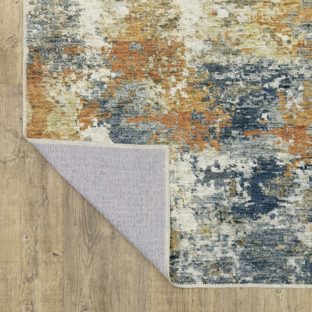 Abstract abstract rug in blue, orange, and cream with a flipped corner showing the backing on a wood floor.