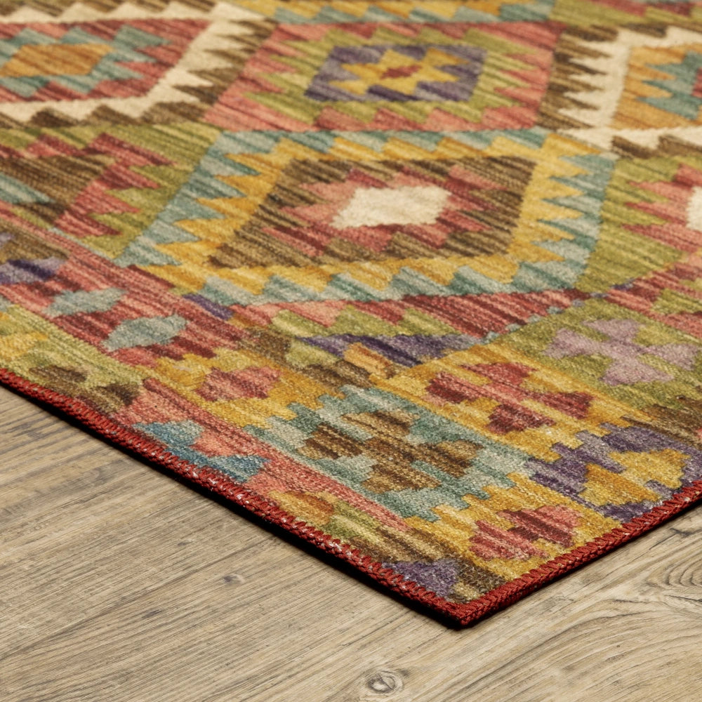 An angled closeup of a multi-colored geometric kilim rug corner with red stitched edges on wood floors.