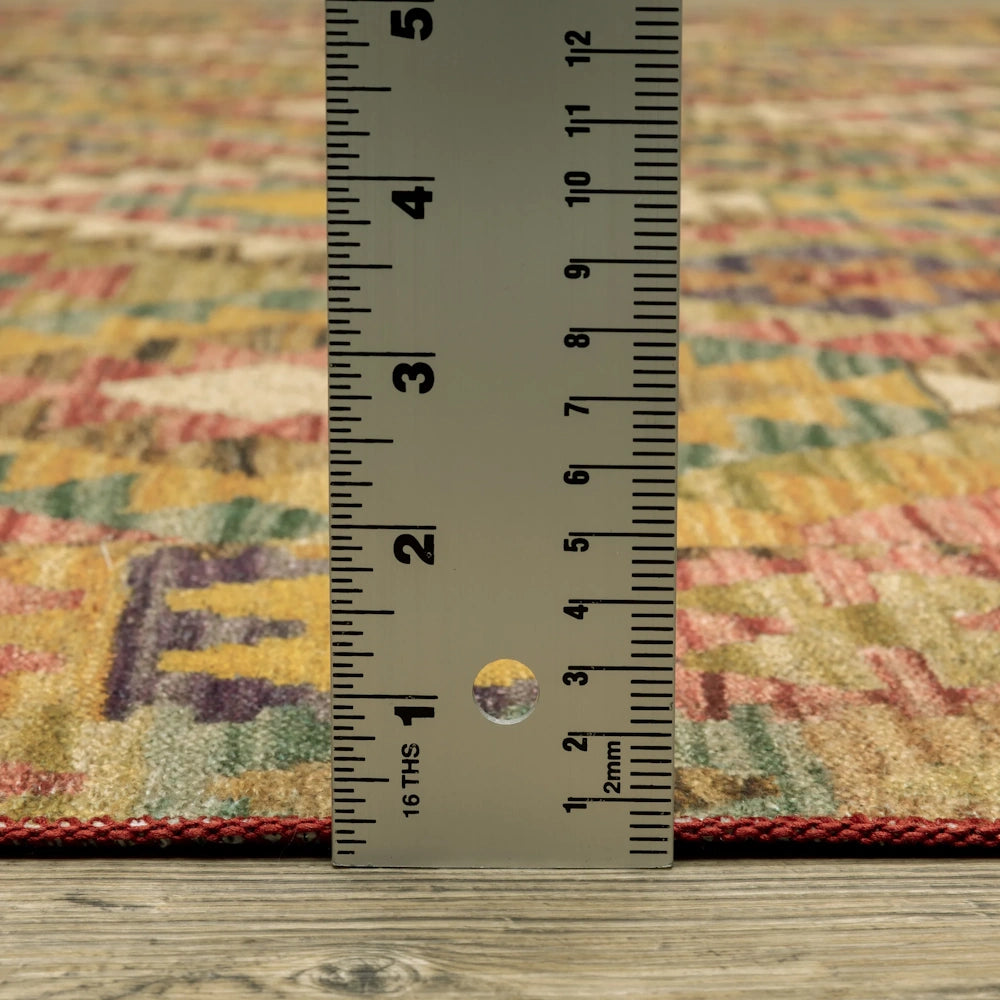 A metal ruler measuring the thin pile height of a colorful patterned rug on a wood floor.