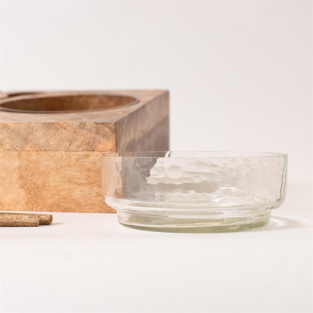 Close-up of a clear textured glass serving bowl alongside a natural wooden base block.