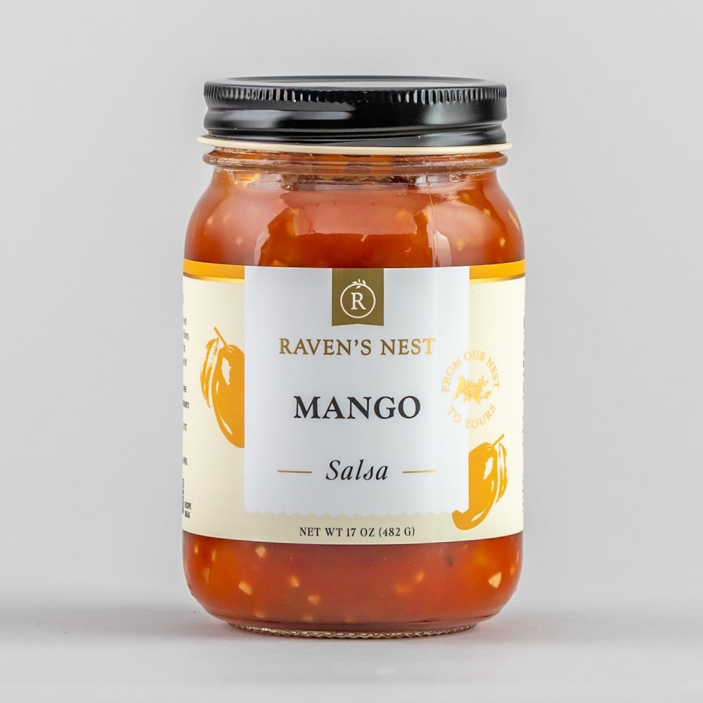 A jar of Raven's Nest Mango Salsa with a white and yellow label featuring illustrations of mangoes.