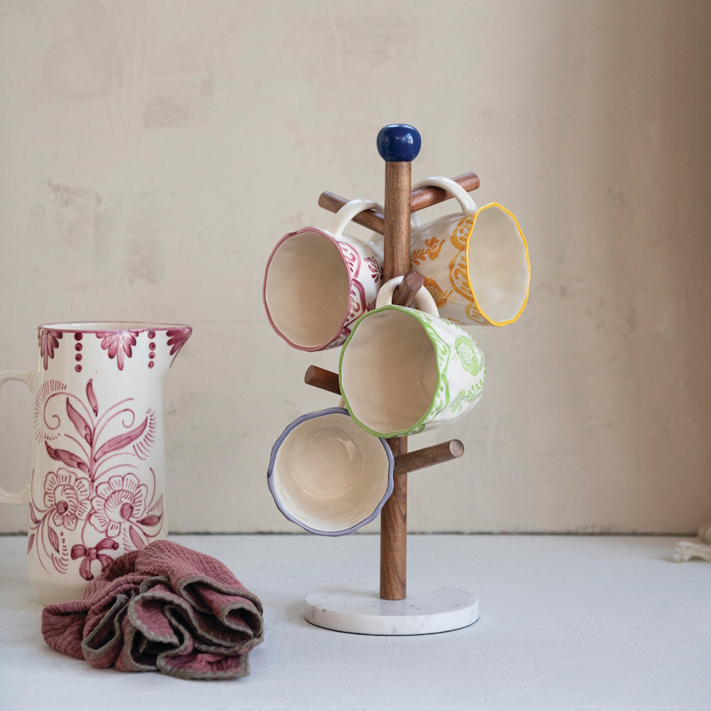 Mango wood mug rack with marble base holding colorful patterned ceramic coffee cups.