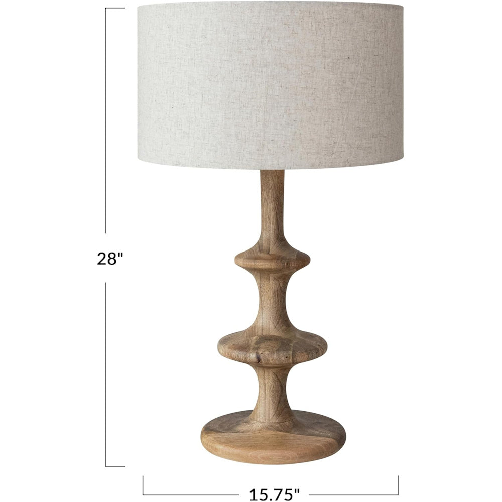 28-inch carved wood table lamp with a natural linen drum shade and tiered pedestal base.