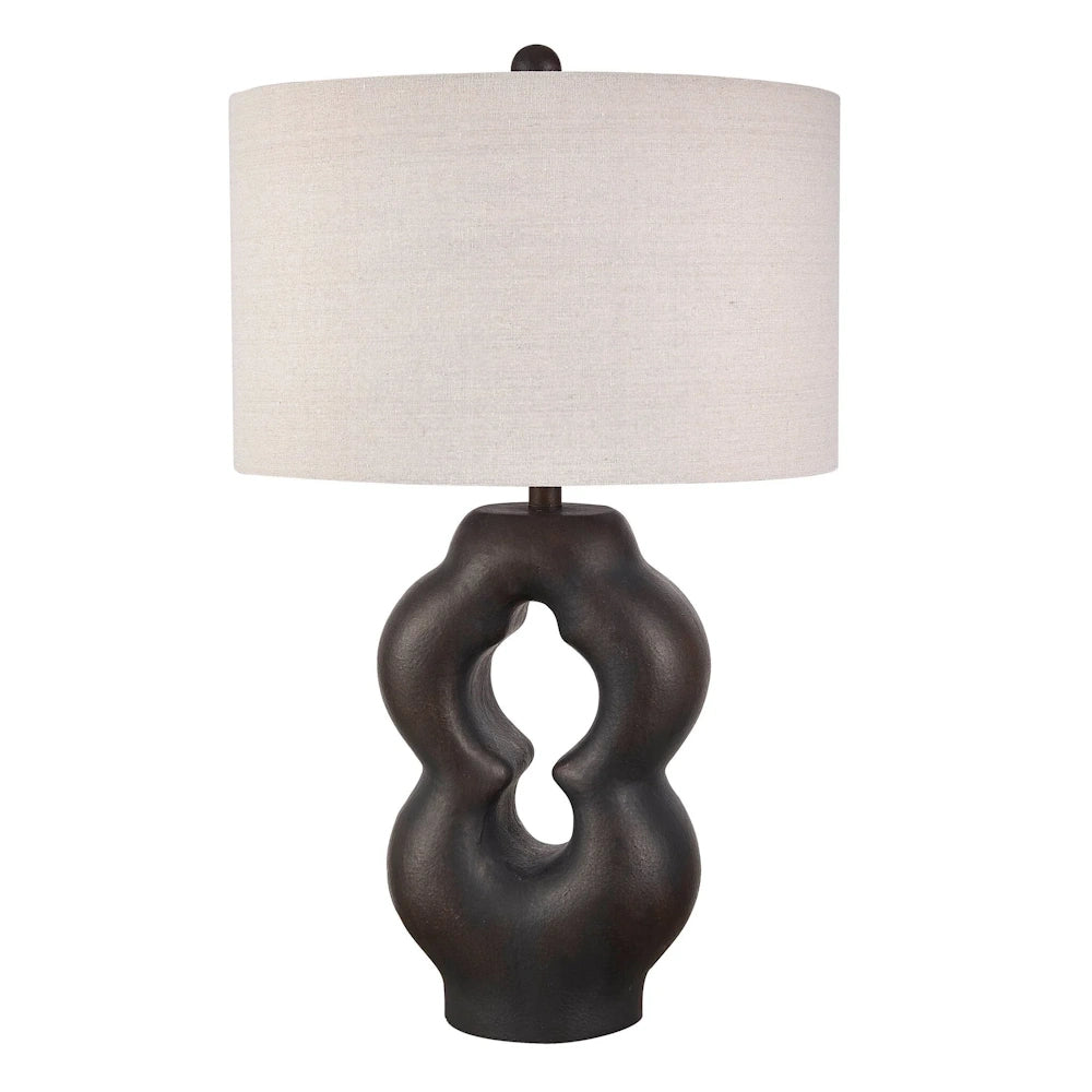 Sculptural bronze table lamp with a modern organic wavy base and a cream linen drum shade for contemporary home decor.