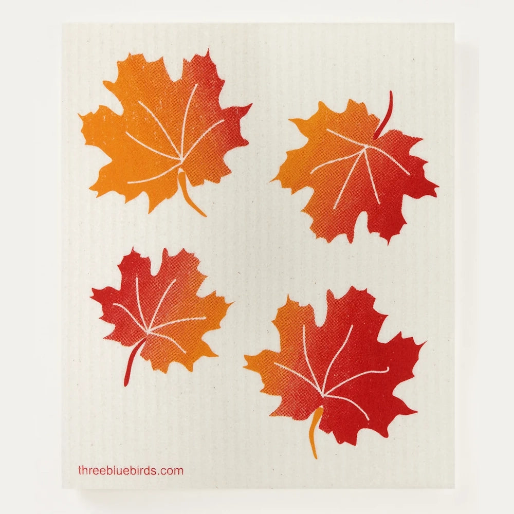 Swedish dishcloth featuring four red and orange gradient autumn maple leaves on a beige background.