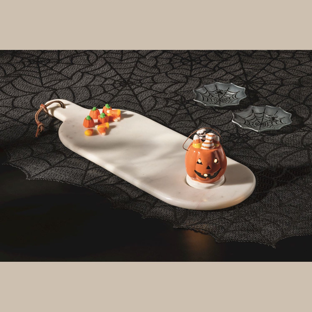 Halloween marble serving board with pumpkin candy corn sitter on a spiderweb lace tablecloth.