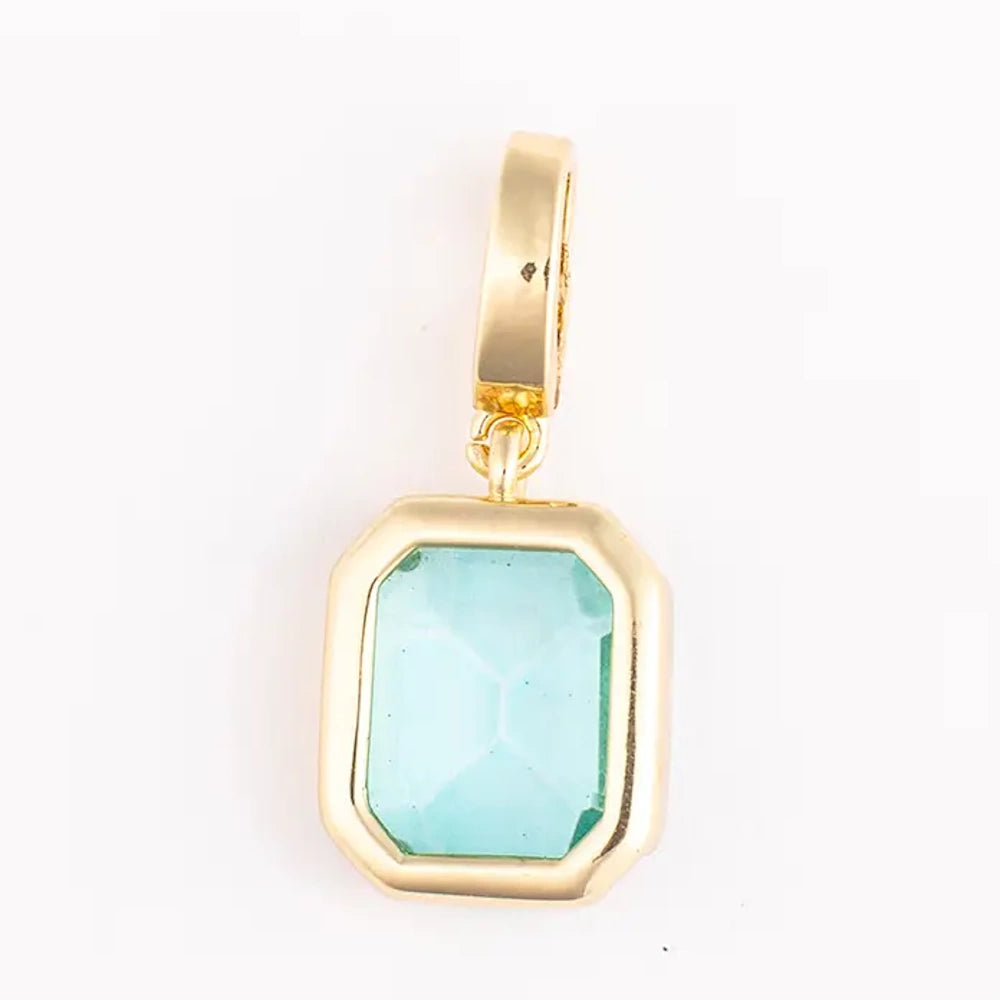 Gold pendant charm featuring an emerald-cut, light aqua-blue gemstone in a polished bezel setting.