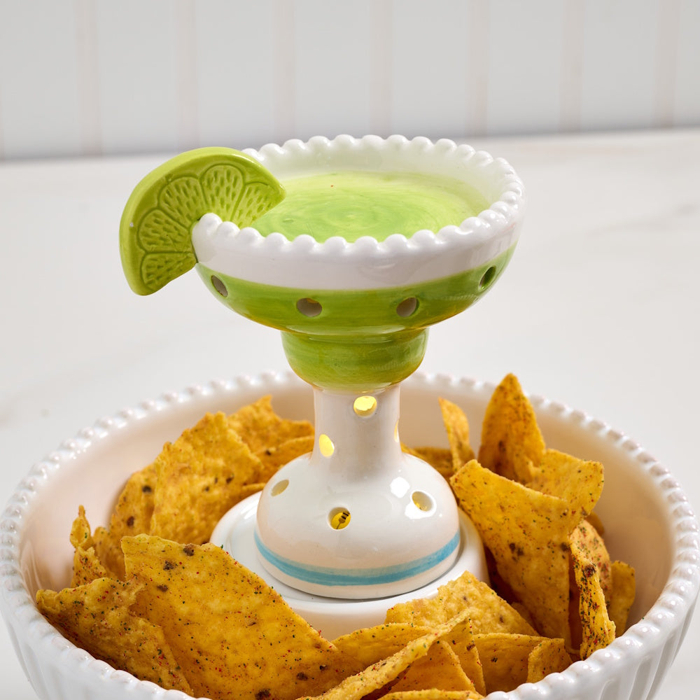 Ceramic margarita light-up sitter decoration inside a white beaded bowl filled with seasoned tortilla chips.