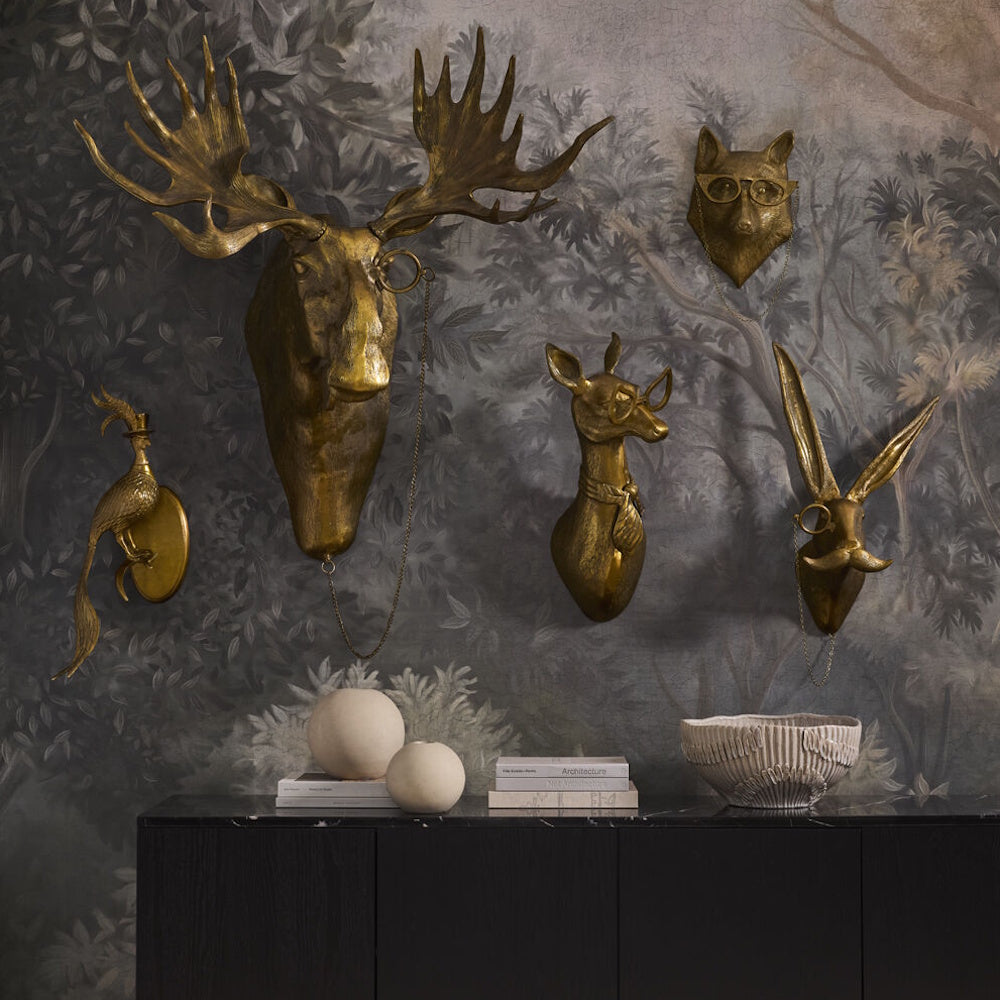 Five bronze animal head wall mounts with glasses and monocles, arranged over a black console table.