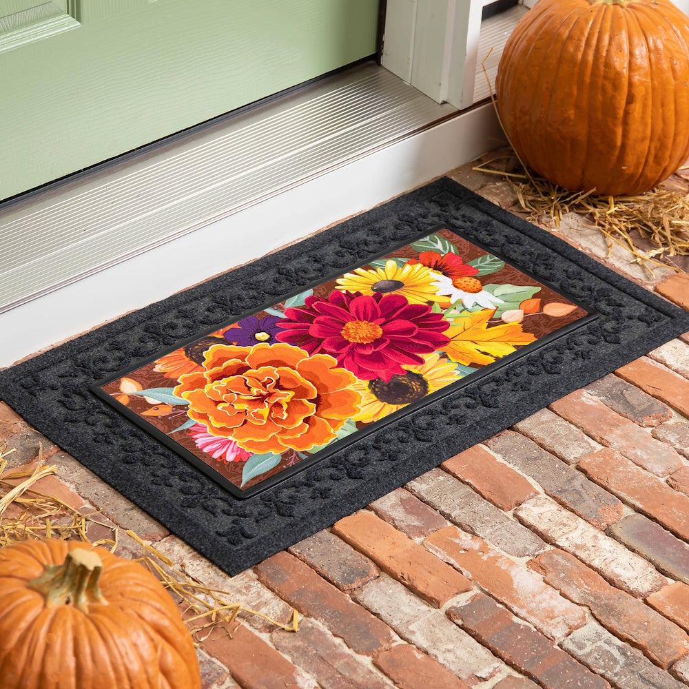 Colorful floral door mat with pumpkins on a brick porch. Perfect autumn home decor and seasonal entryway accent.