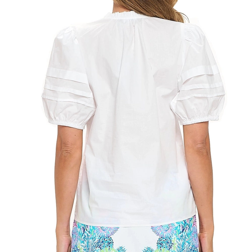 Back view of a woman wearing a white short-sleeve top with puff sleeves, pleat details, and a ruffled neckline.