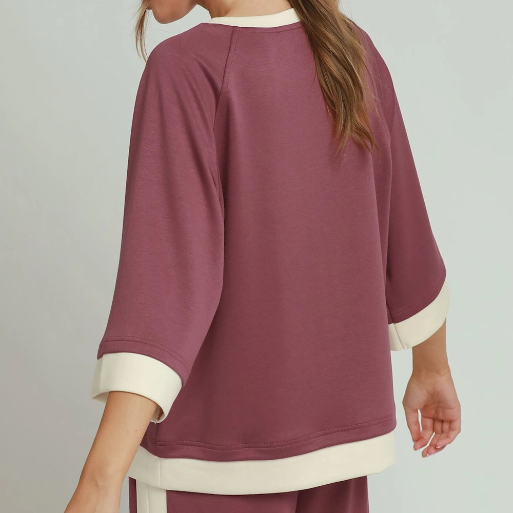 Woman wearing a maroon colorblock raglan sleeve top with cream trim, back view.