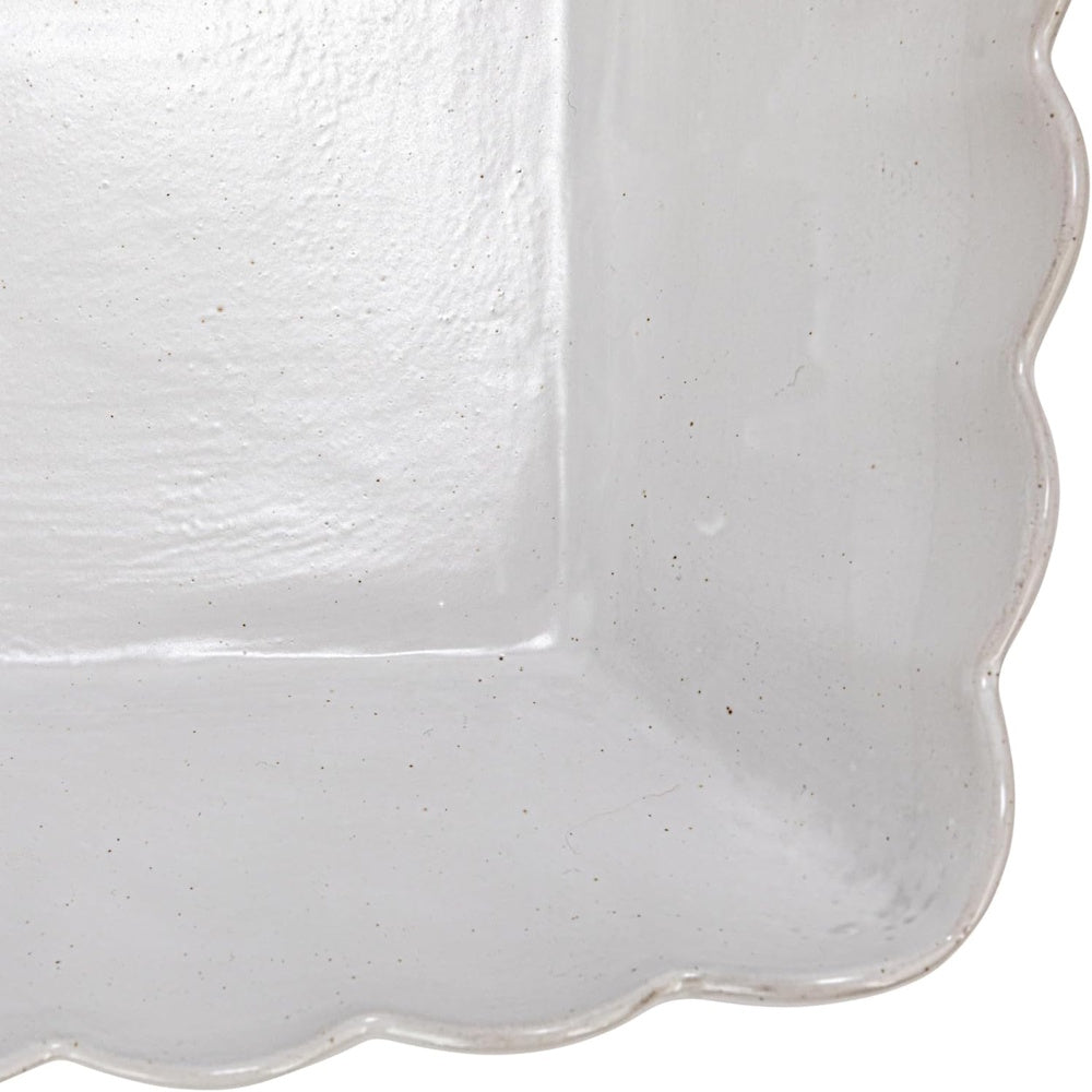 Close-up of a matte white square stoneware bowl featuring a scalloped edge and textured speckled finish.