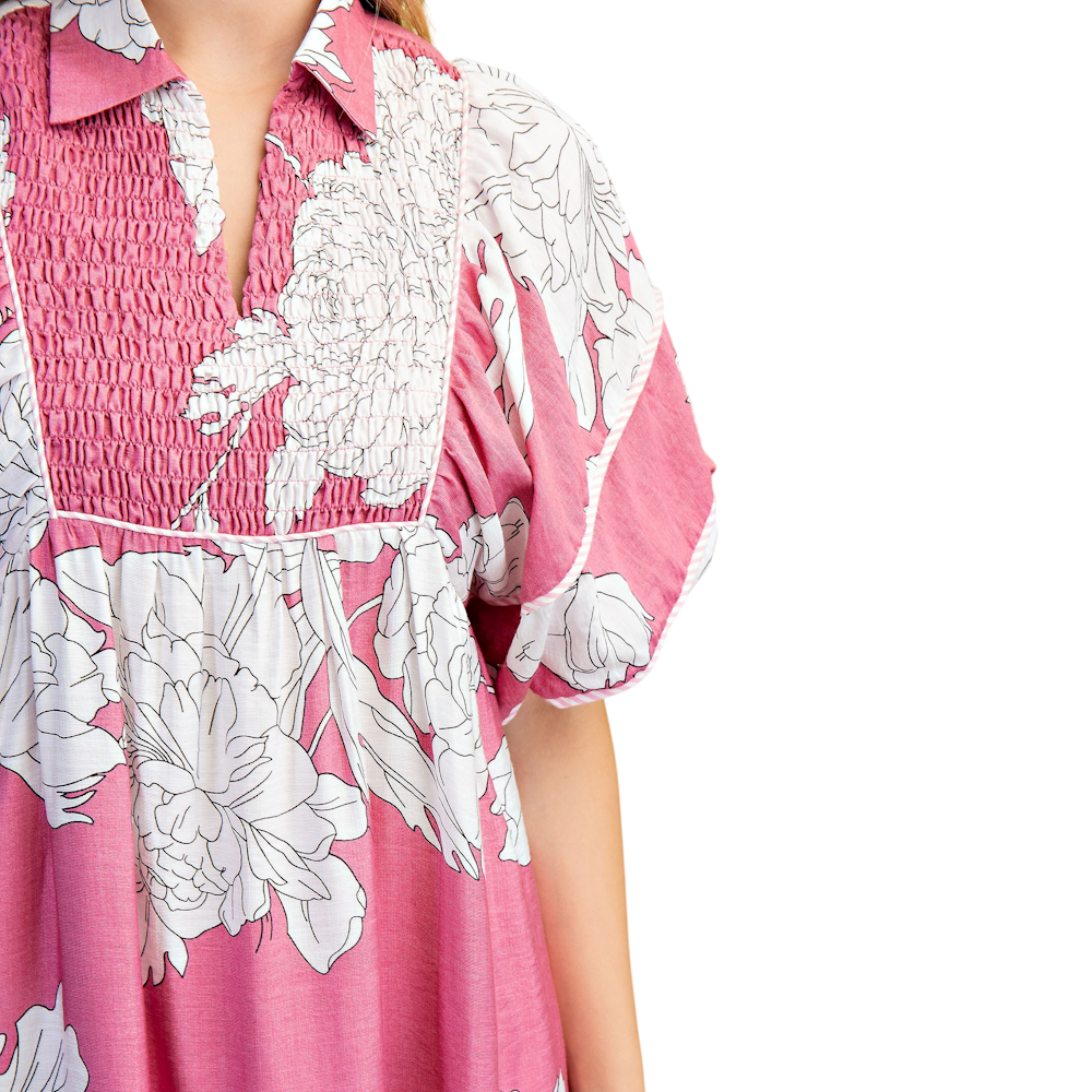 Close-up of a pink and white floral dress with a smocked bodice and short puff sleeves.
