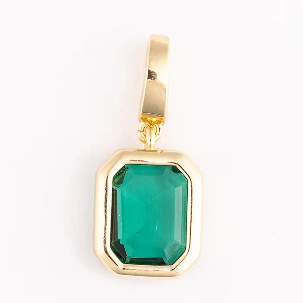 Gold charm featuring a rectangular emerald-cut green gemstone set in a thick gold frame.
