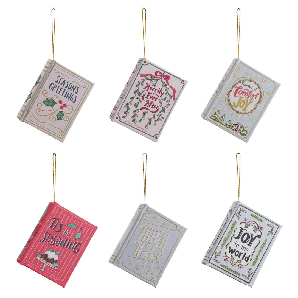 Set of six miniature book-shaped Christmas ornaments with festive holiday covers and hanging strings.