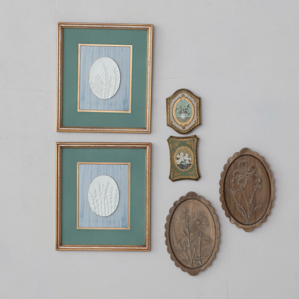 Vintage botanical gallery wall featuring framed art and small MDF wall decor with flowers in a vase.