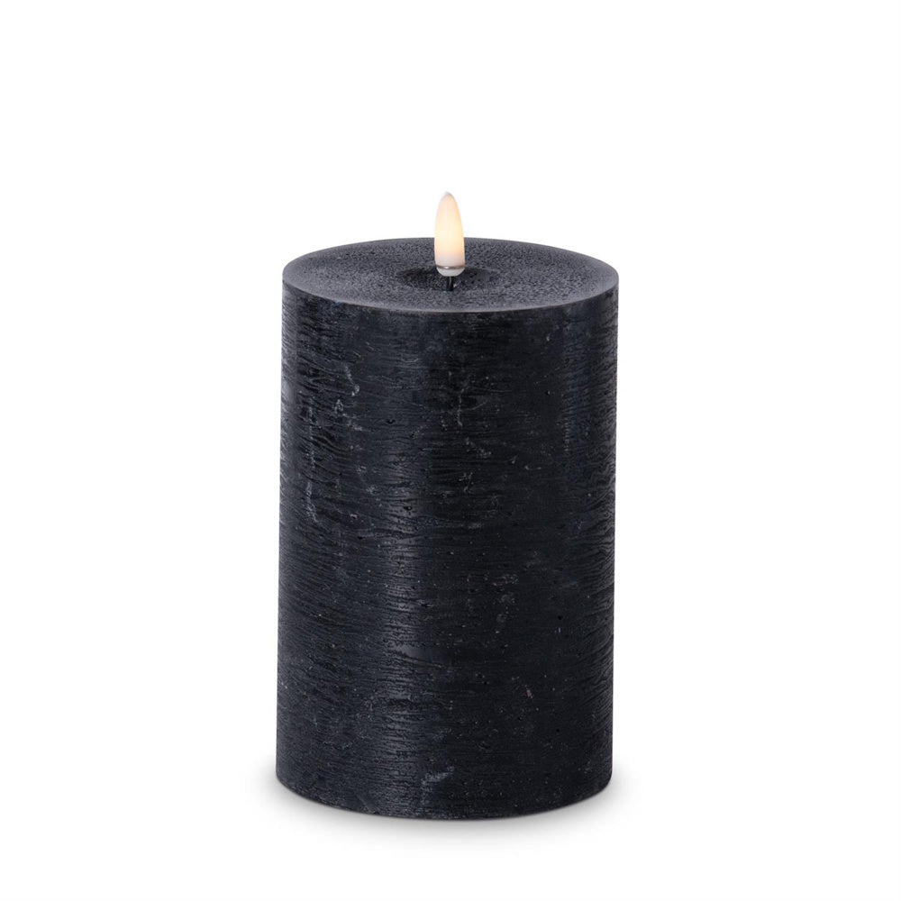 Medium-height black textured flameless LED pillar candle with a warm glowing faux flame.