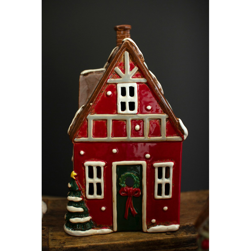 Red ceramic Christmas village house featuring white trim, a green wreath, and snow accents.