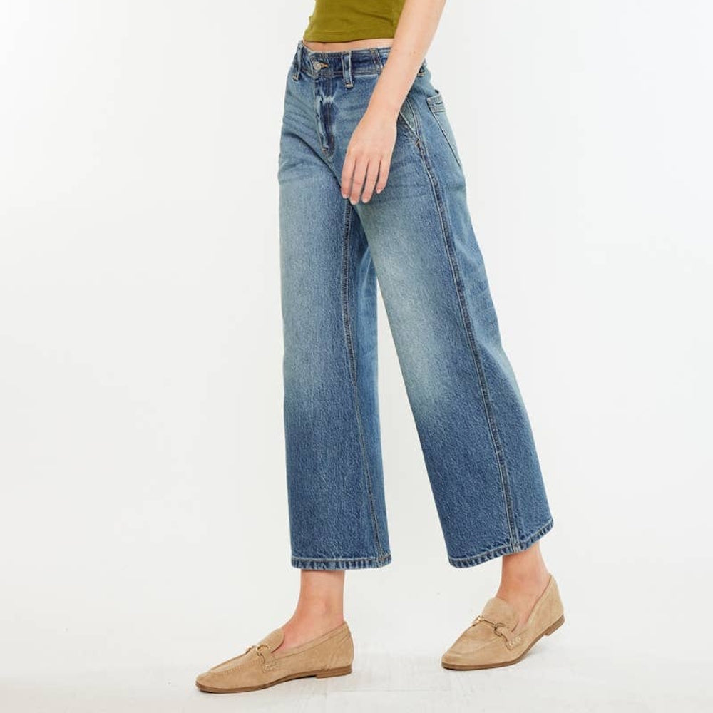 Side view of a person wearing medium-wash, loose barrel-leg jeans styled with beige loafers.