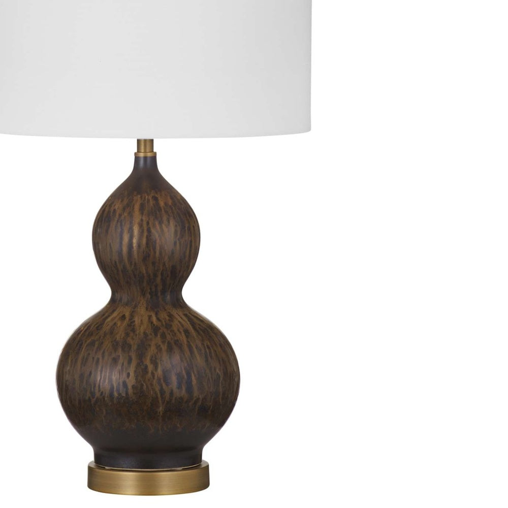 Close-up of a double-gourd table lamp base in textured mottled bronze on a brass stand with a white shade.