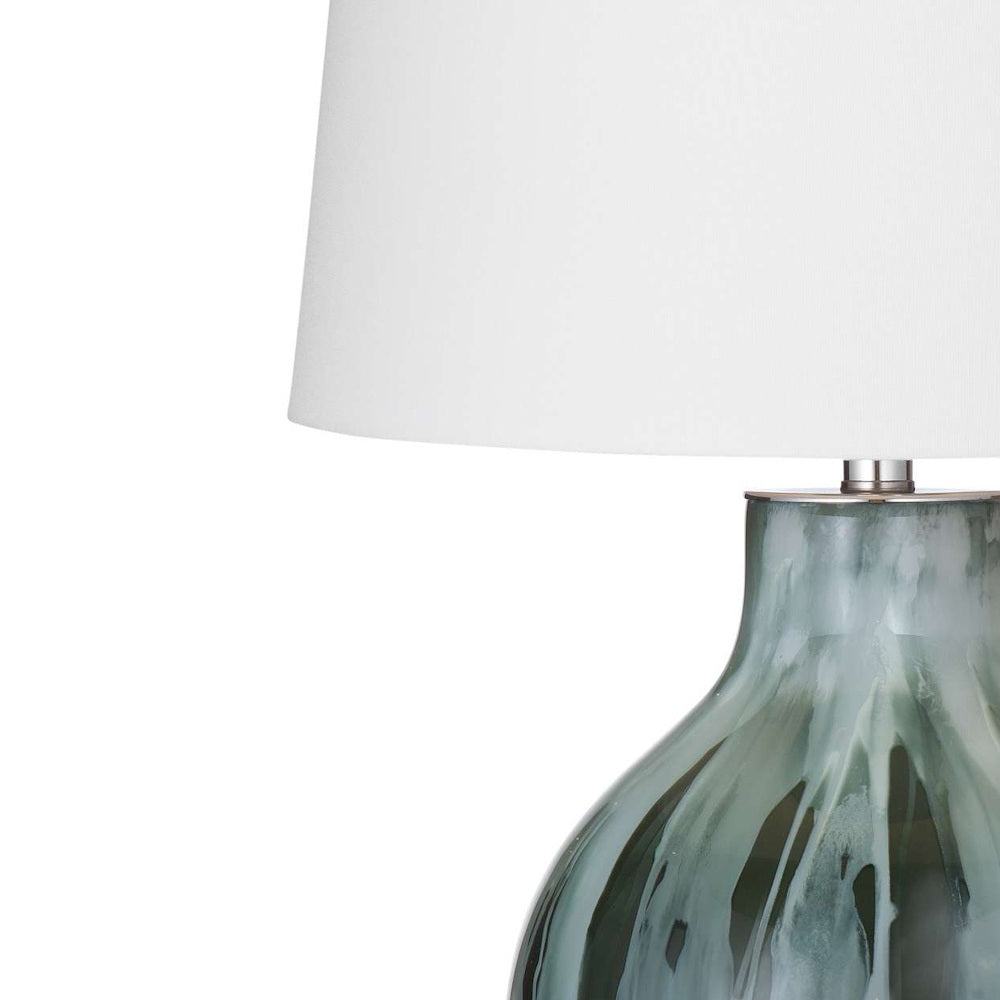 Close-up of a table lamp with a white fabric shade and a marbled teal and grey glass base.