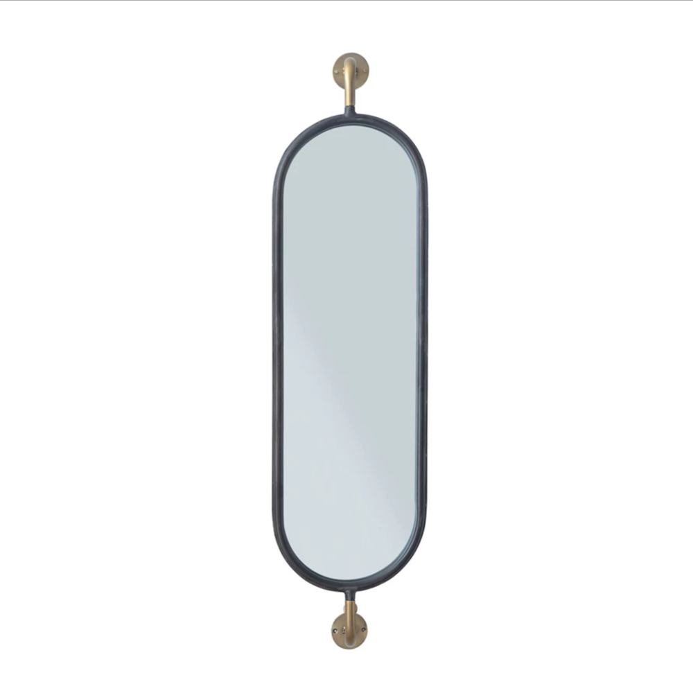 Long oval pill-shaped wall mirror with a black metal frame and decorative brass mounting brackets at the top and bottom.