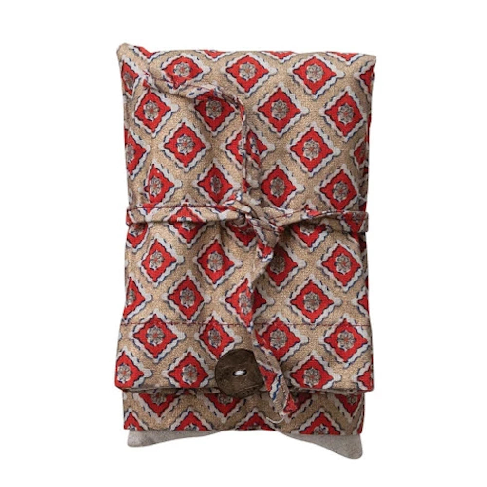 Microwaveable hot and cold pack with a red and gold diamond pattern, lavender and lentil filled with a wooden button closure.