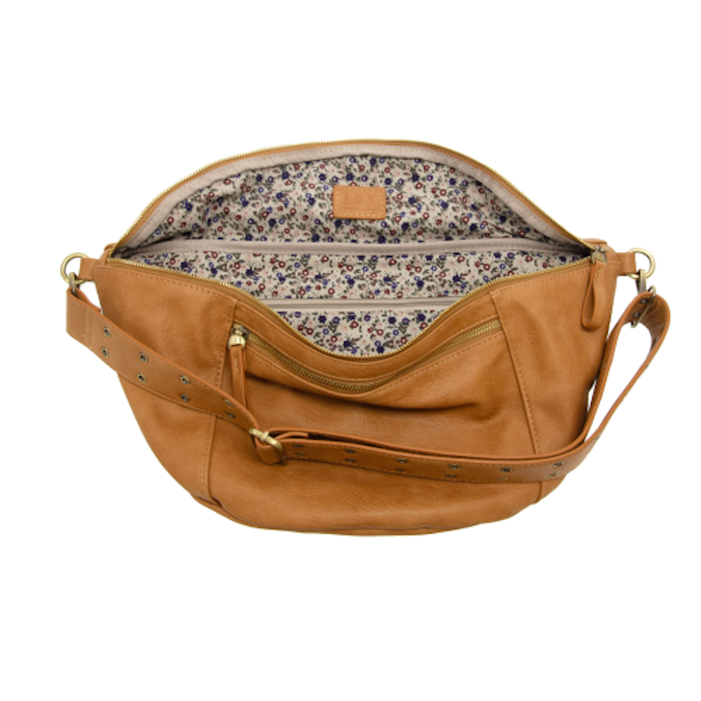 Open tan leather crossbody fanny pack with floral lining and studded adjustable strap.