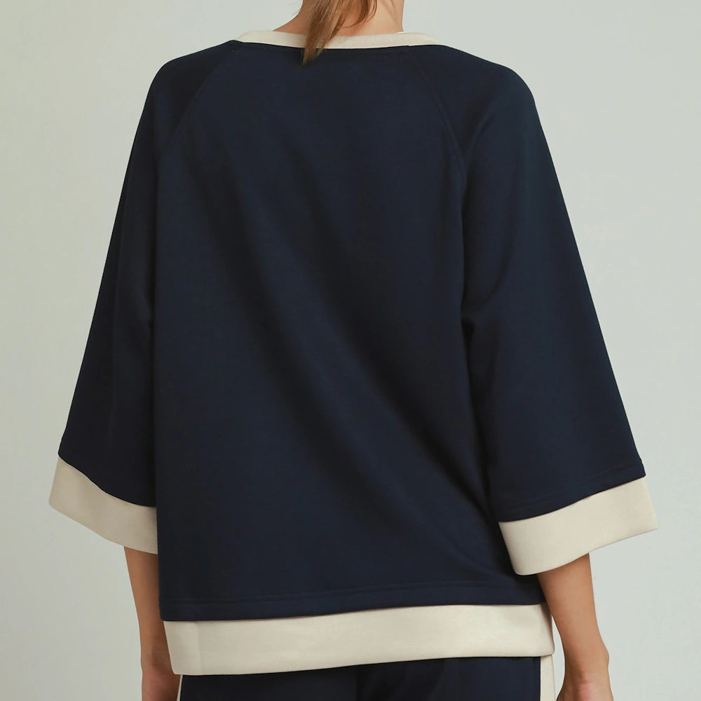 Back view of a midnight blue colorblock crewneck top with raglan sleeves and cream trim.