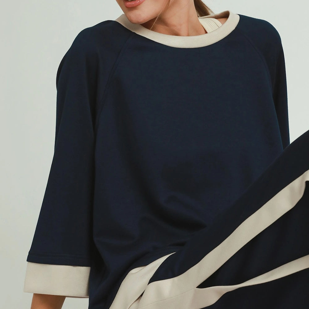 Midnight blue crewneck top with beige contrast trim on collar and raglan sleeves.