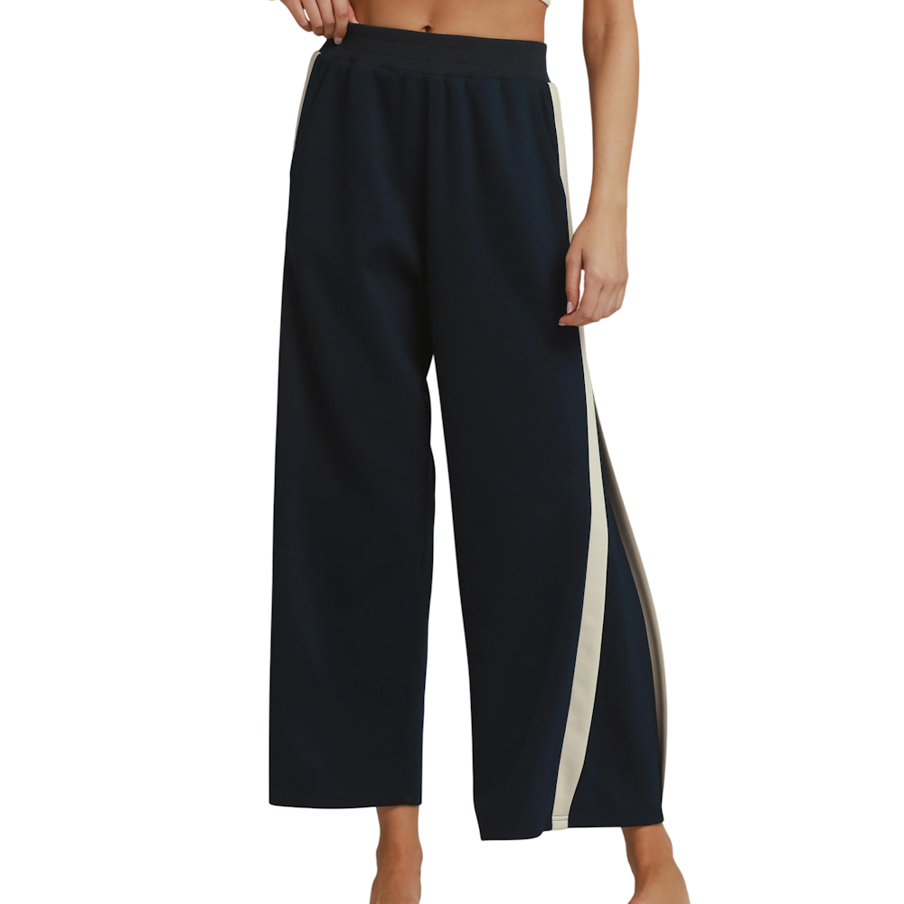 Midnight blue wide-leg track pants featuring cream colorblock side stripes and an elastic waist.