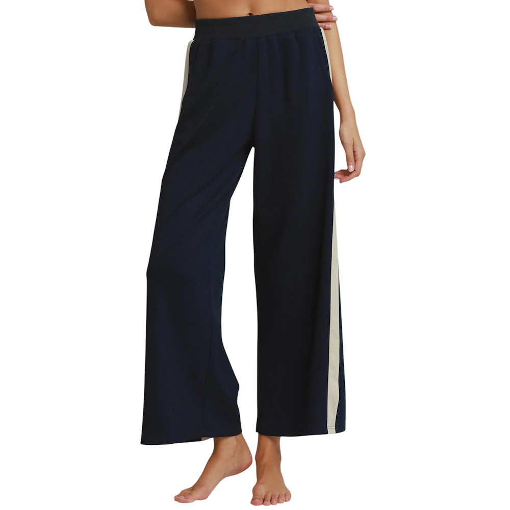 Woman wearing midnight blue wide-leg knit pants with contrasting cream side stripes and an elastic waist.