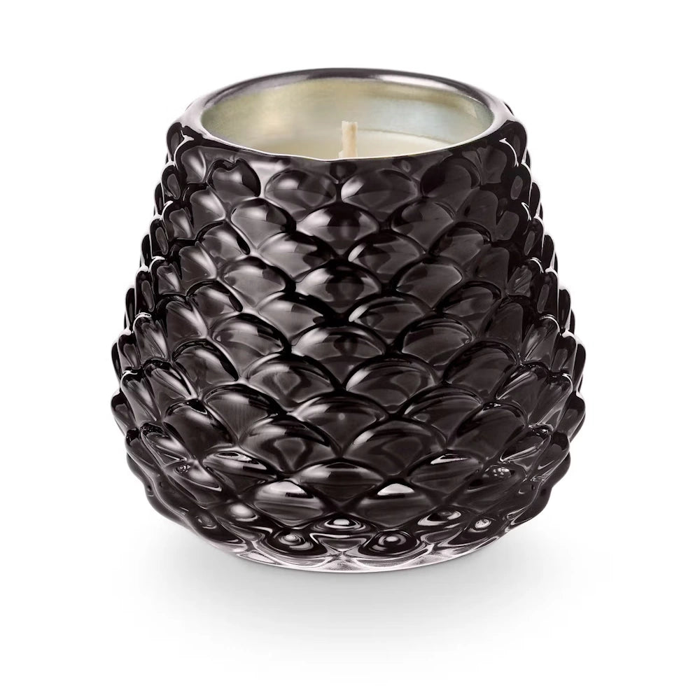 Glossy black textured pinecone votive candle holder with a white wax candle inside on white background.
