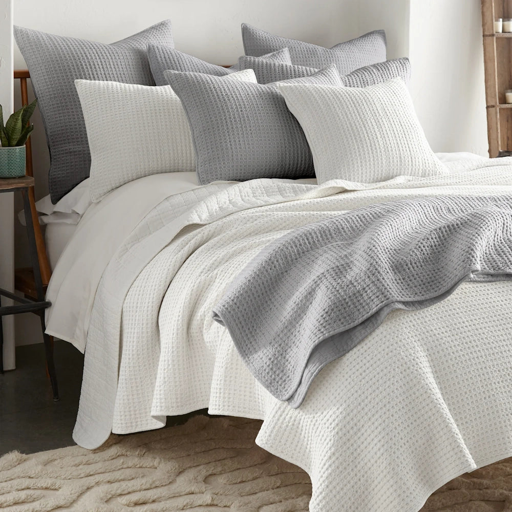 White and grey waffle weave quilt set with matching textured pillows on a modern bed.