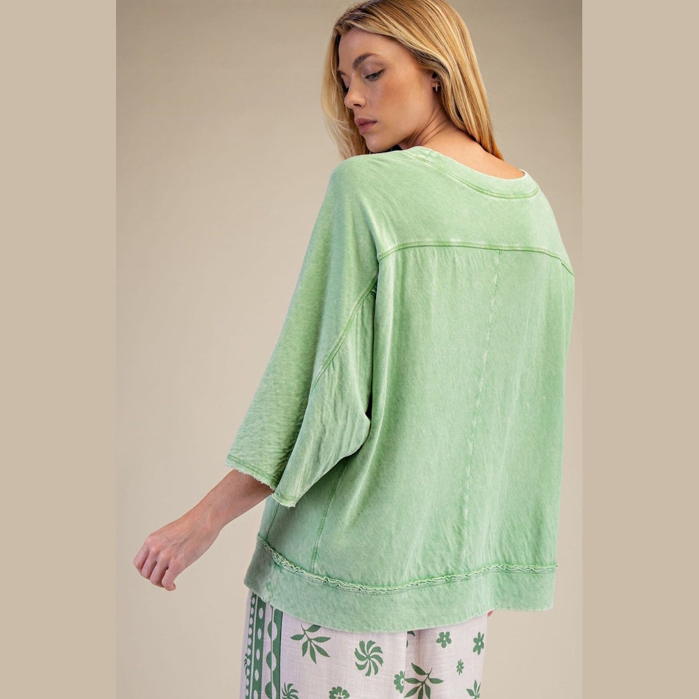 Back view of a woman wearing a lime green mineral-washed cotton gauze boxy knit top with raw-edge hem detailing.