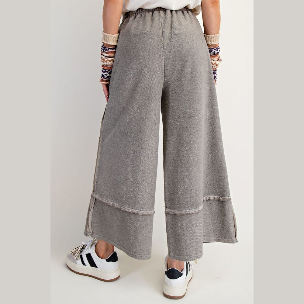 Back view of mineral washed, grey wide-leg palazzo pants with raw-edge seams and elastic waistband.