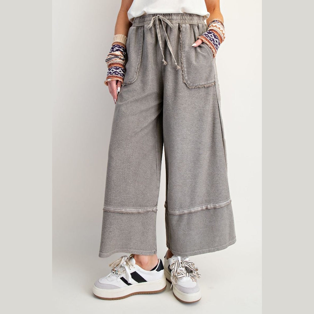 Mineral wash grey wide-leg palazzo pants featuring a drawstring waist, raw edge pockets, and a comfortable terry knit.
