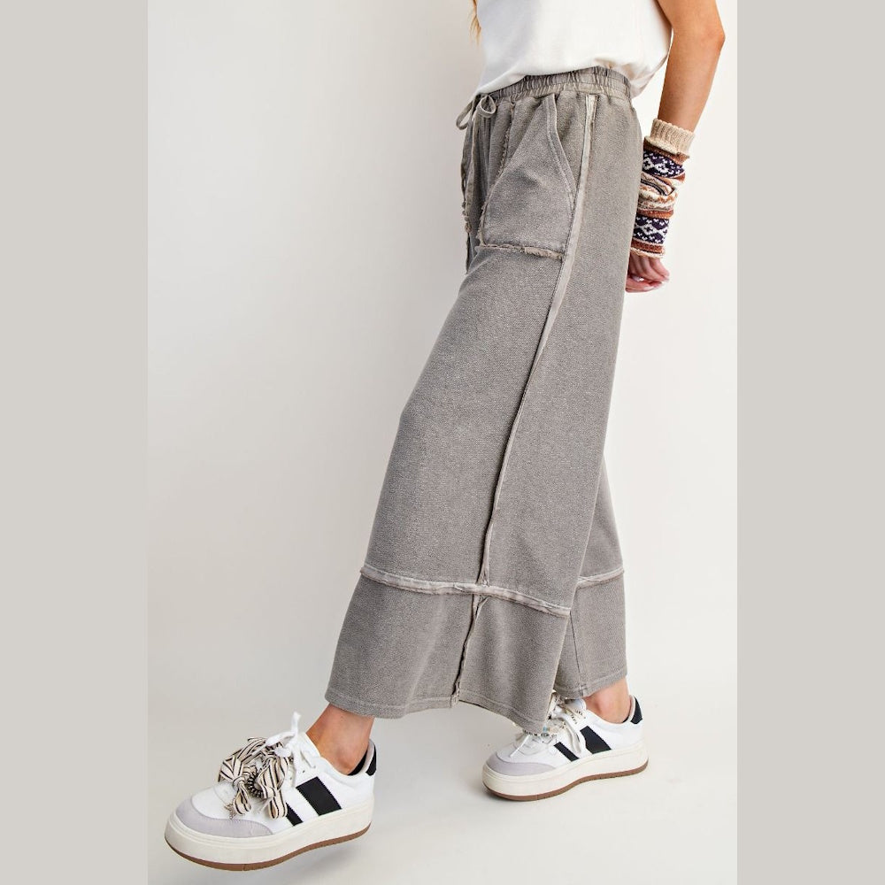 Mineral-washed grey wide-leg palazzo pants with exposed seams and raw edges.