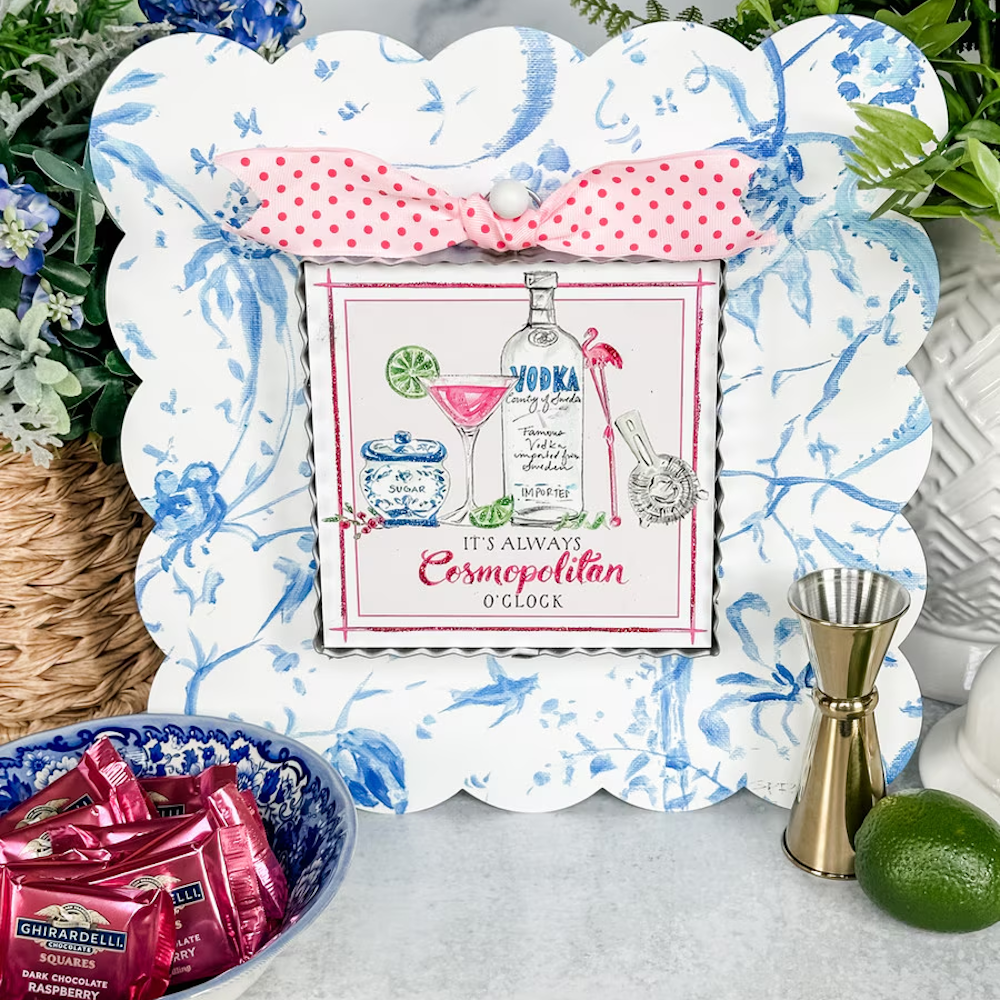 Cosmopolitan cocktail art with a pink bow, vodka bottle, and lime, framed by blue floral scalloped patterns.
