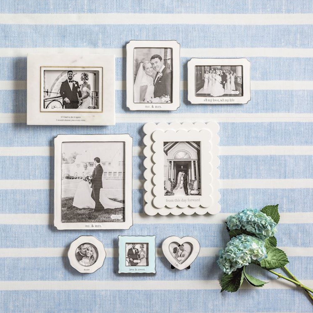 An arrangement of eight small, white-rimmed wedding photo frames on a blue and white striped background with blue hydrangeas.