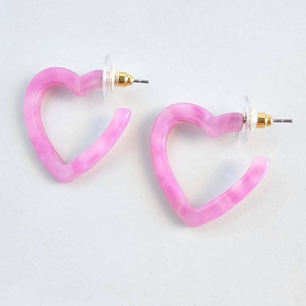 Pink marble resin mini heart hoop earrings with gold posts on a white background.