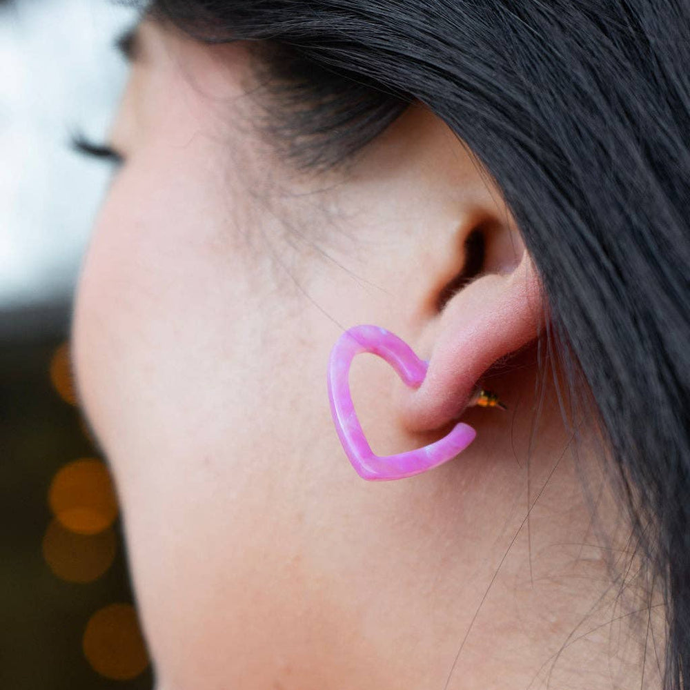 Close-up of a person wearing a pink marble resin mini heart hoop earring.