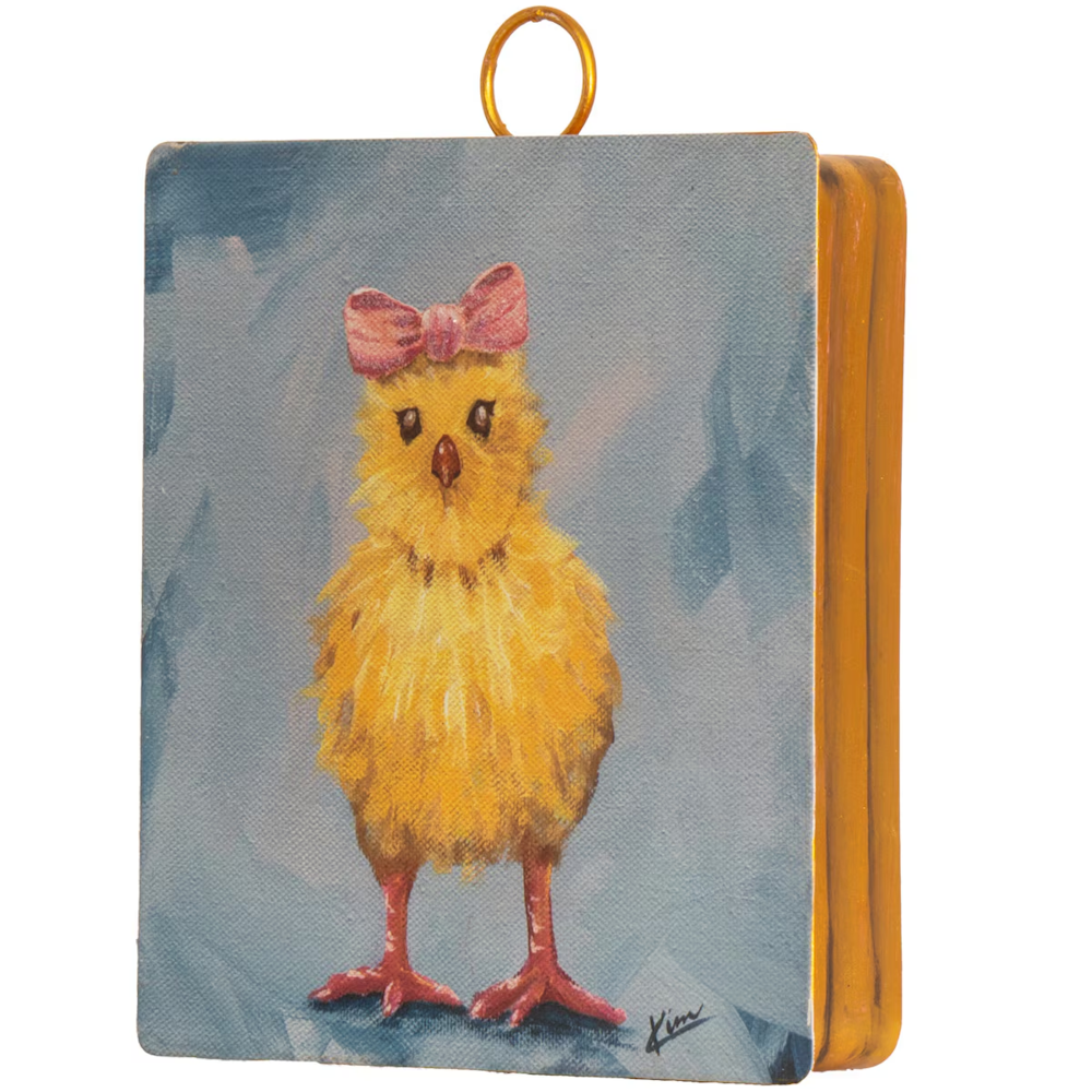 Oil painting of a yellow chick with a pink bow on its head, featured on a small canvas with a gold metal loop.