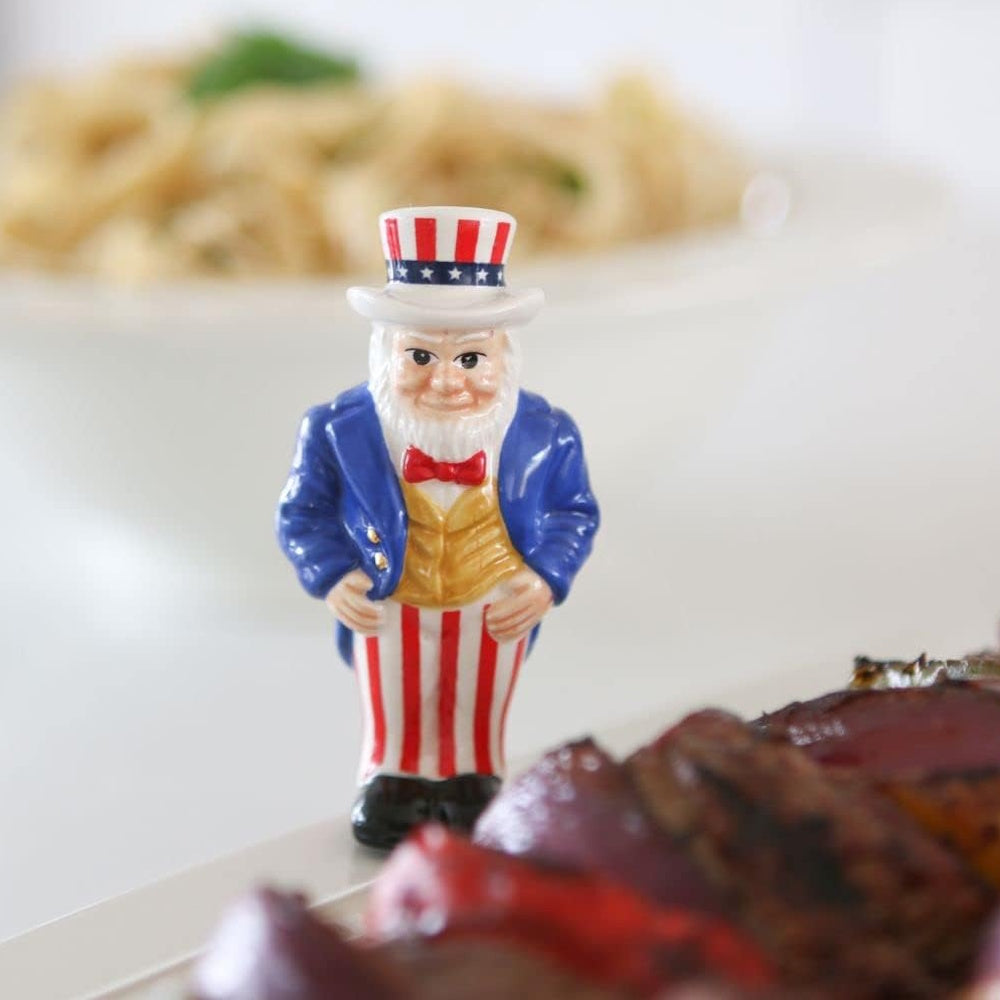 A small Uncle Sam figurine standing on a table next to a plate of food.